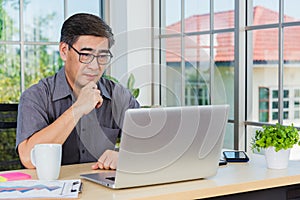 Asian senior business man working online on a modern laptop computer