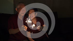 Asian senior couple celebrating together at home sparkles firework s