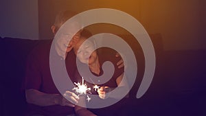 Asian senior couple celebrating together at home sparkles firework s