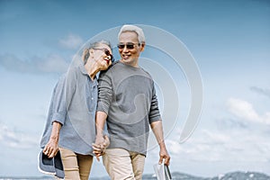 Asian senior couple or elderly people walking and siting at the beach