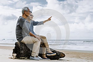 Asian senior couple or elderly people walking and siting at the beach