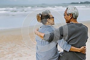 Asian senior couple or elderly people walking and siting at the beach