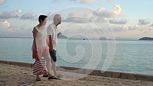 Asian senior couple elderly walking coastline beach morning anniversary retirement trip