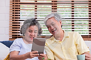 Asian senior couple learn to using table compute on sofa in living room at home.senior with technology lfiestyle.aging at home