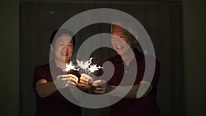 Asian senior couple playing sparklers, fire cracker at night. Concept celebrating life