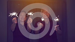 Asian senior couple playing sparklers, fire cracker at night. Concept celebrating life