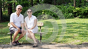 Asian senior couple sitting at bench in the park with copy space