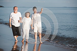 Asian senior couple and son walking on summer beach sunset. Travel leisure and activity after retirement on vacations and summer