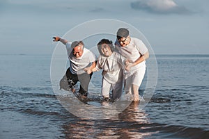 Asian senior couple and son walking on summer beach sunset. Travel leisure and activity after retirement on vacations and summer