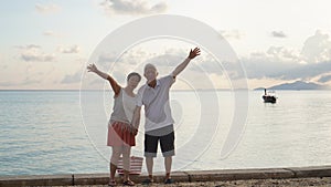 Asian senior couple standing playing at beach sunrise sea early morning relaxed happy natural retirement life