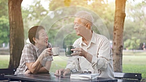 Asian senior couple start morning coffee in park, optimistic con