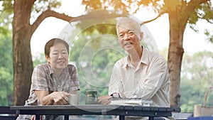 Asian senior couple start morning coffee in park, optimistic con