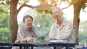 Asian senior couple start morning coffee in park, optimistic con