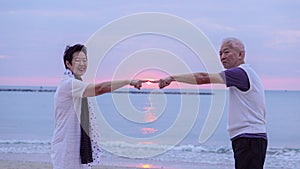 Asian senior couple together at sunrise beach. New year, new chapter concept