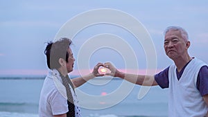 Asian senior couple together at sunrise beach. New year, new chapter concept