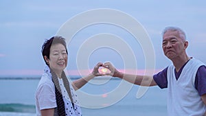 Asian senior couple together at sunrise beach. New year, new resolution concept