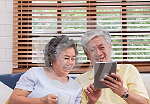 Asian senior couple using table compute and drink coffee sitting at sofa in living room at home.senior with technology lfiestyle.a