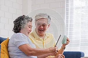 Asian senior couple using table compute and drink coffee sitting at sofa in living room at home.senior with technology lfiestyle.a