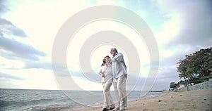 Asian senior couple walking and talking on beautiful tropical beach.