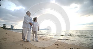 Asian senior couple walking and talking on beautiful tropical beach.