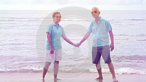 Asian senior couple walking together on the beach by the sea