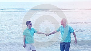 Asian senior couple walking together on the beach by the sea