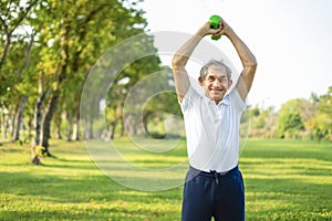 asian senior doing exercise with dumbbell in the summer park