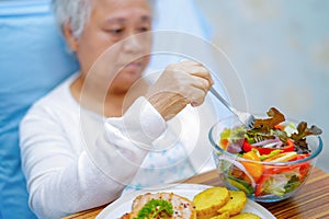 Asian senior eating breakfast in hospital.