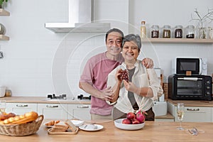 Asian senior eating fruits together in her modern kitchen