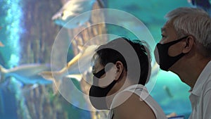 Asian senior elder couple dating in Aquarium new normal with mask fun happy relax trip together
