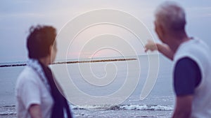 Asian senior elder couple holding hands looking sunset sea ocean together happy retirement life