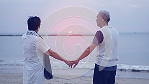 Asian senior elder couple holding hands looking sunset sea ocean together happy retirement life