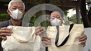 Asian senior elder couple wearing mask encourage using cotton bag recycleable for grocery shopping