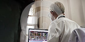 Asian senior elder man working on computer exhaustly at work from home office wearning mask and glasses