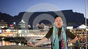 Asian senior elder travel to South Africa Cape town V and A waterfront landmark at night sunset behind table mountain scenic