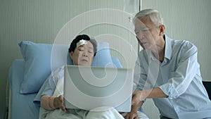Asian senior elderly couple discuss medical data on computer screen in hospital bed
