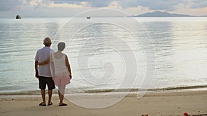 Asian senior elderly couple hugging in morning sunrise relax life travel to the beach tropical sea view