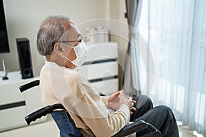 Asian Senior Elderly disabled lonely man wear mask, sit on wheelchair. Mature older guy feel upset while stay at nursing home care