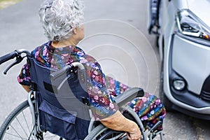 Asian senior or elderly lady woman patient sitting on wheelchair prepare get to her car : healthy strong medical concept.