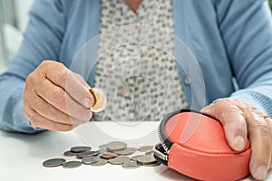 Asian senior or elderly old lady woman holding counting coin money in purse. Poverty, saving problem  in retirement