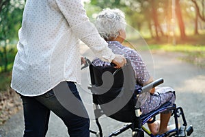 Asian senior or elderly old lady woman patient with care, help and support on wheelchair in park in holiday