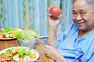 Asian senior or elderly old lady woman patient eating breakfast healthy food with hope and happy while sitting and hungry on bed
