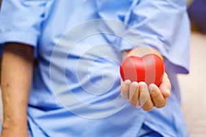 Asian senior or elderly old lady woman patient holding red heart in her hand.