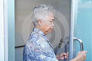 Asian senior elderly old lady woman patient open toilet bathroom by hand in nursing hospital ward.