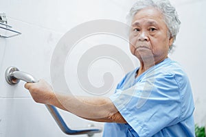 Asian senior or elderly old lady woman patient use toilet bathroom handle security in nursing hospital ward.