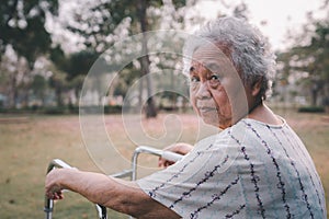 Asian senior or elderly old lady woman patient walk with walker in park with copy space, healthy strong medical.
