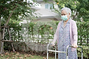 Asian senior or elderly old lady woman walk with walker and wearing a face mask for protect safety infection and kill Novel