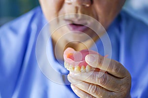 Asian senior or elderly old woman patient holding to use denture in nursing hospital.