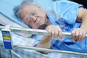 Asian senior or elderly old woman patient lie down handle the rail bed with hope.