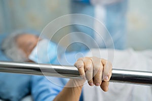 Asian senior or elderly old woman patient lie down handle the rail bed with hope on a bed.